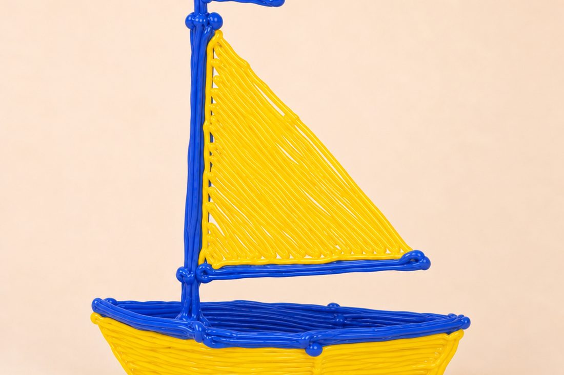 A PCL sailboat with a yellow hull and blue mast, made with a kids' 3D pen